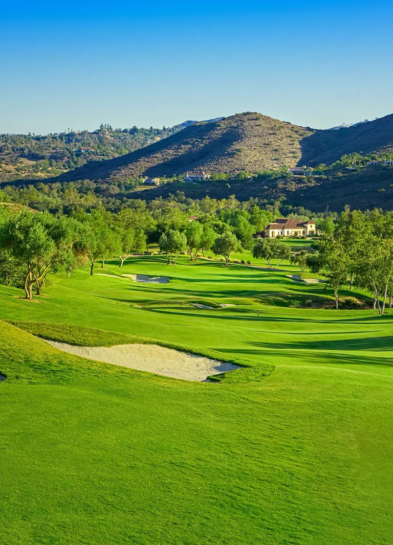 A view of the Maderas Golf Club showing the golf field and a mountain at the back